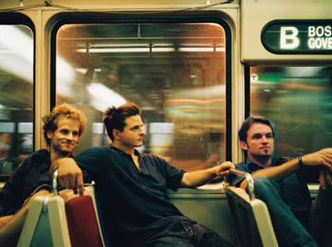 Three men sitting on a subway train.