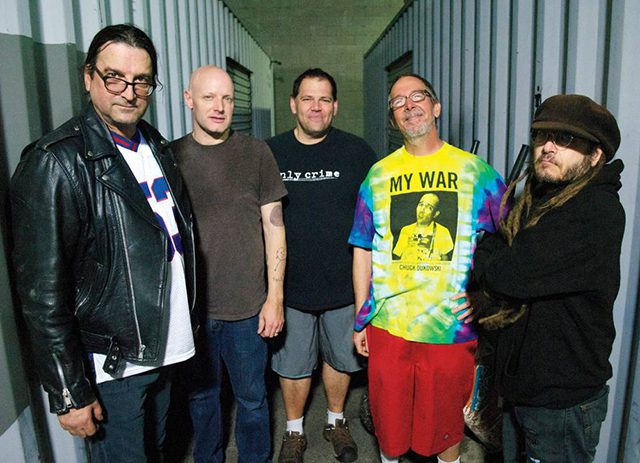 Five men standing in a row, smiling.