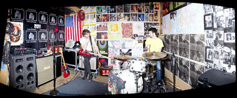 Band rehearsing in a colorful, poster-filled room.