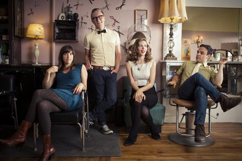 Four people sitting in a retro salon.