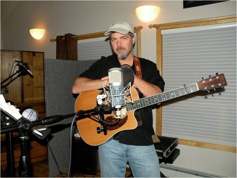 Man playing guitar in a recording studio.