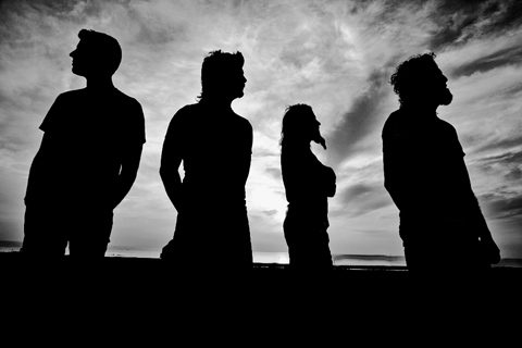 Silhouettes of four people against cloudy sky.