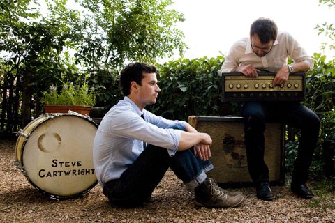 Two men with musical equipment outdoors.