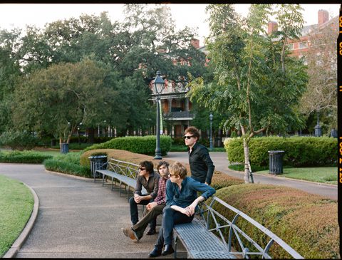 Four people sitting on park benches outdoors.
