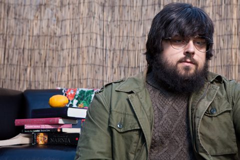 Man sitting beside books on a sofa.