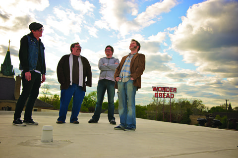 Four people standing on a rooftop smiling.
