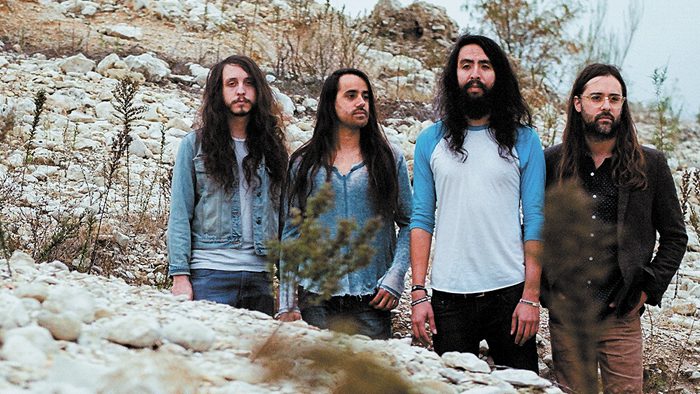Four men standing on rocky terrain outdoors.