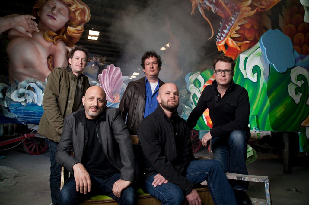 Five men posing in front of parade float.