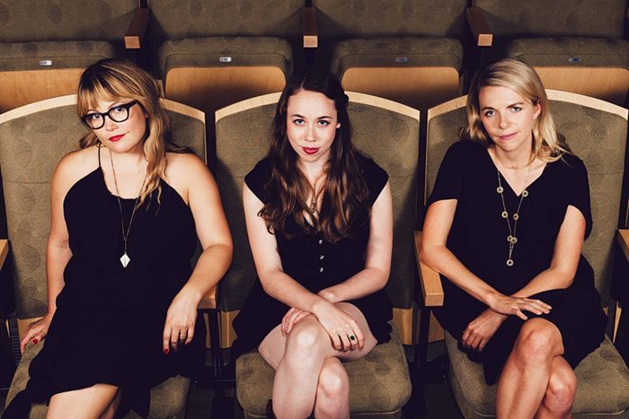 Three women sitting in theater seats.