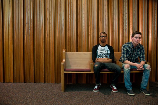 Two men sitting on a wooden bench.