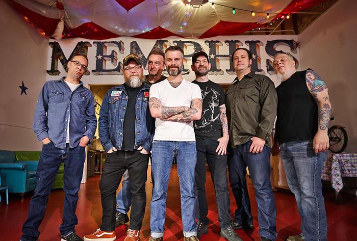 Seven men posing in front of Memphis sign.