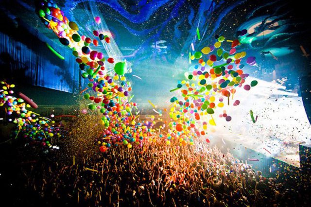 Concert crowd with balloons and confetti celebration.
