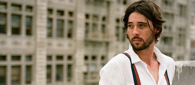 Man in white shirt with suspenders outdoors.