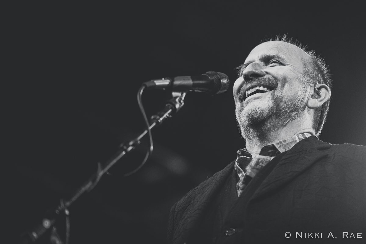 Smiling man singing into a microphone.