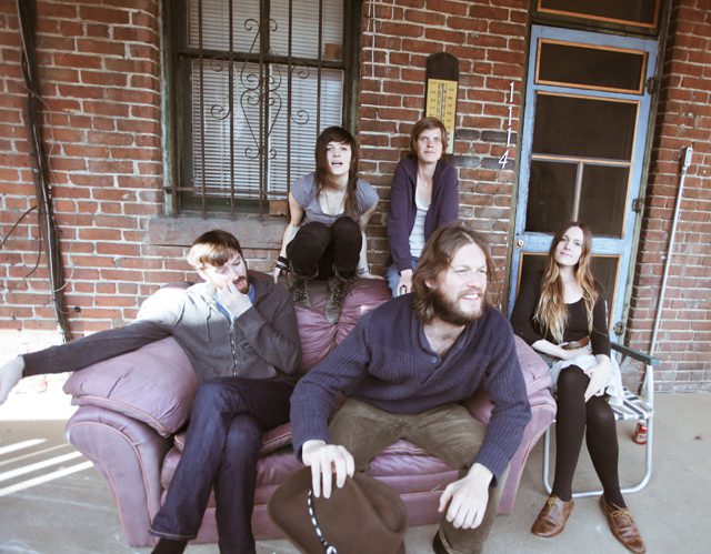 Five people sitting on a porch couch.