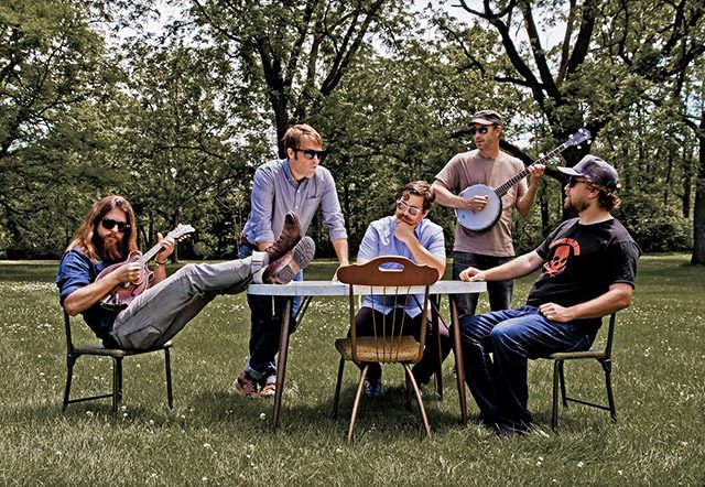 Group of musicians sitting outdoors with instruments.
