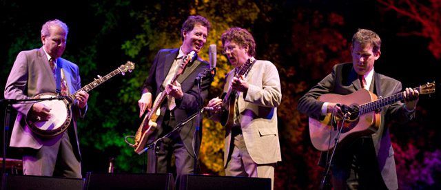 Four musicians performing on stage with instruments.