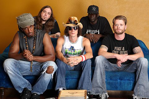 Five men sitting on a blue couch.