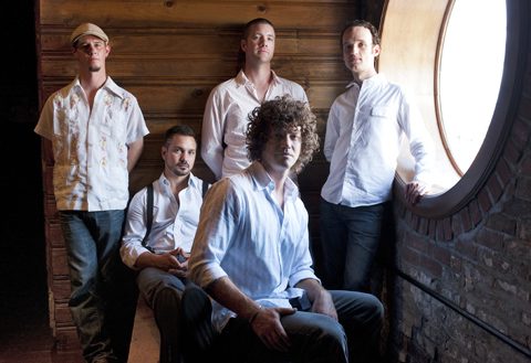 Five men posing near a round window.