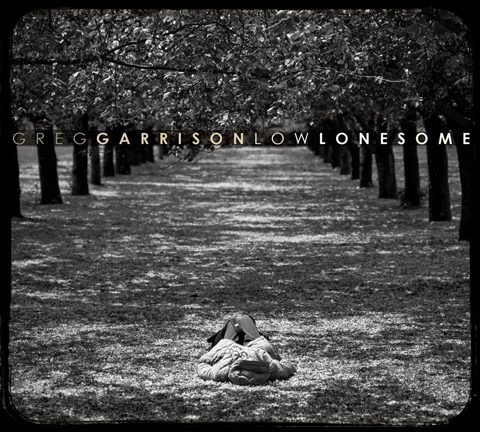 Person lying under trees in a grove.