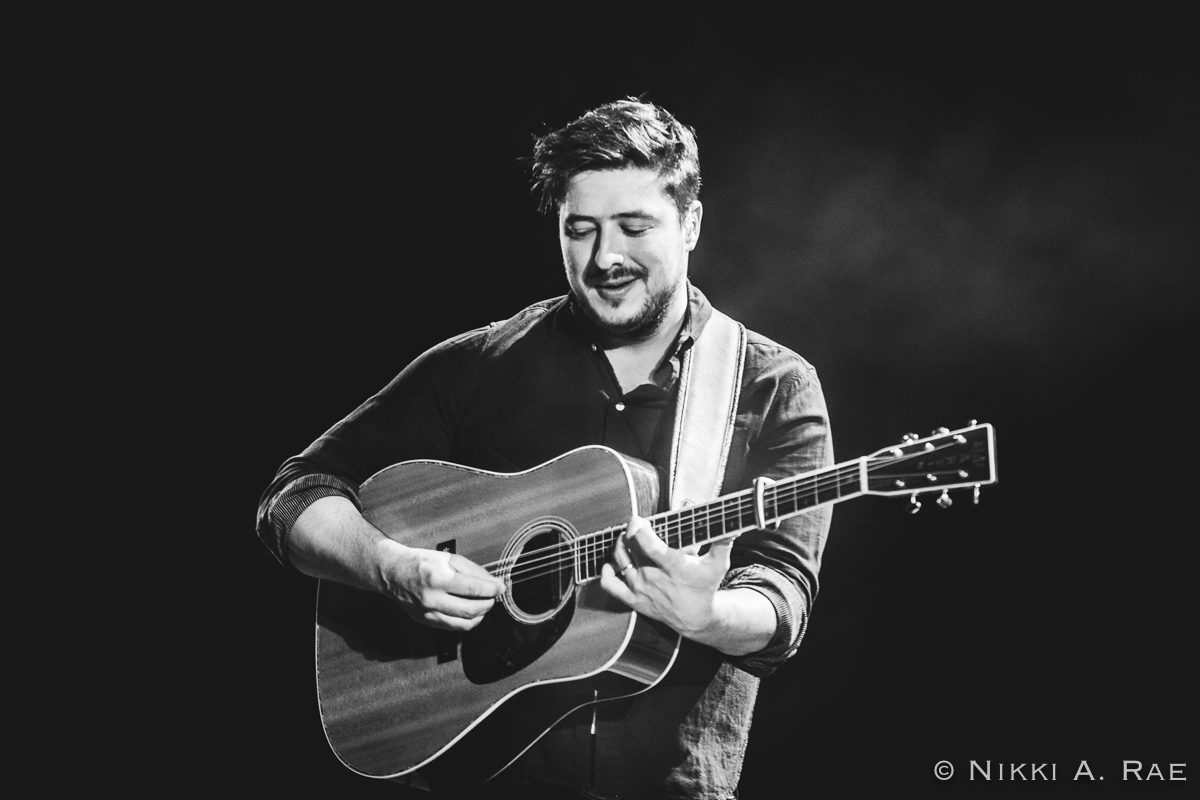 Musician playing acoustic guitar on stage.