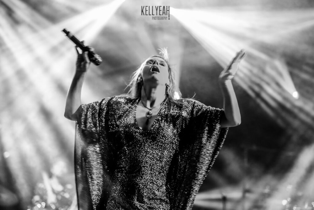 Singer performing passionately on stage with spotlight.