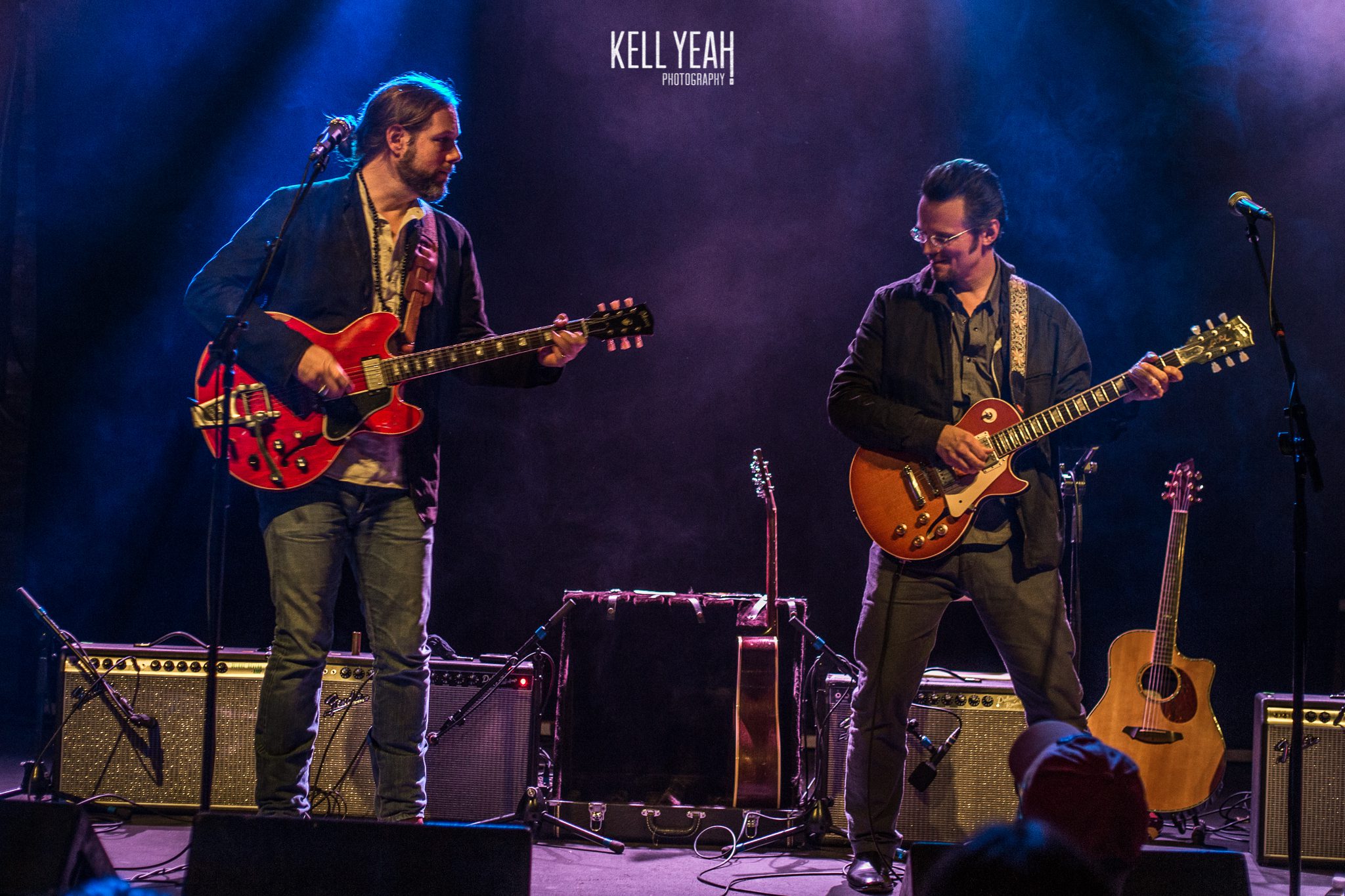 Two musicians playing electric guitars on stage.