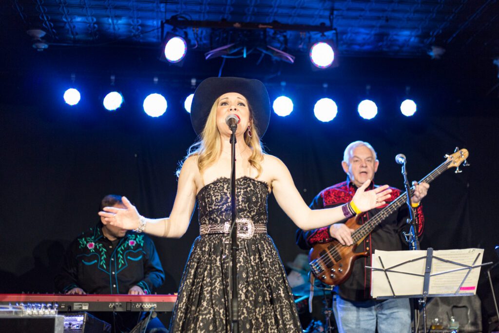 Singer performing on stage with band.