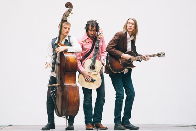 Three musicians playing instruments on stage.