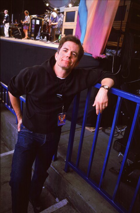 Man leaning on railing at concert stage.