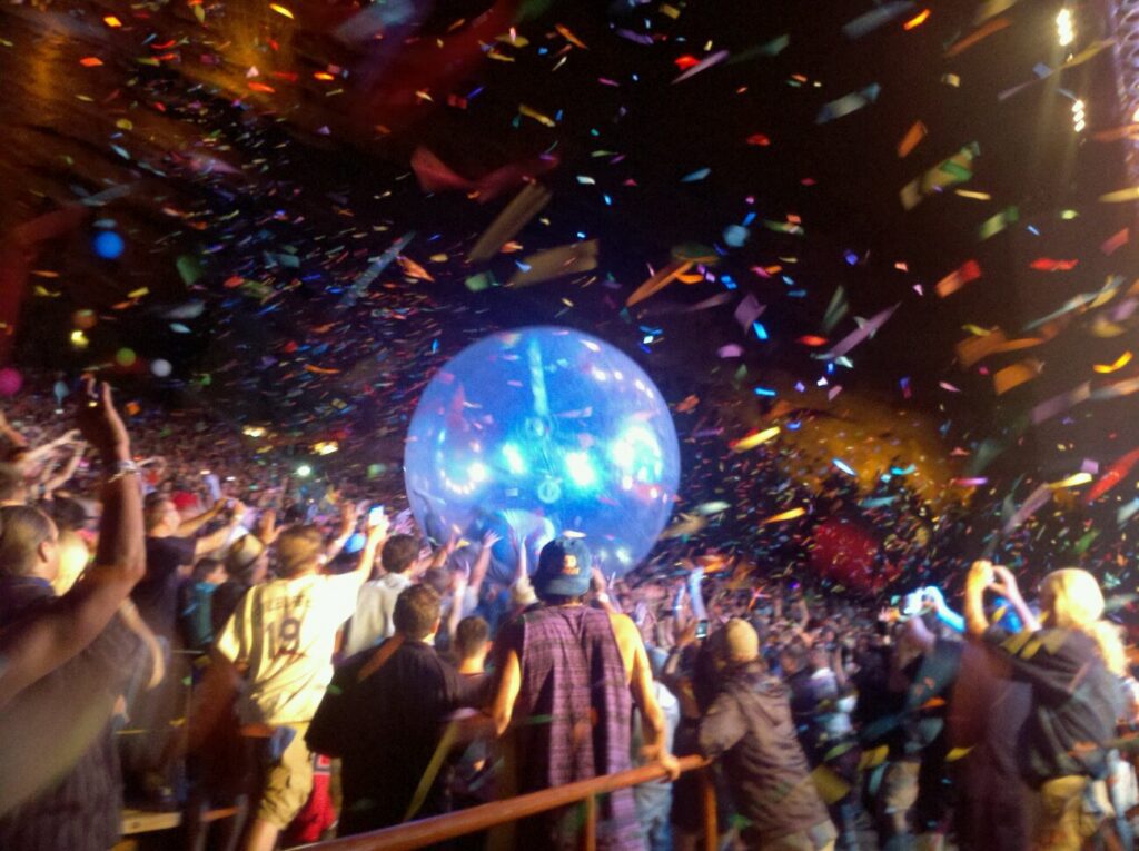 Concert crowd with confetti and giant ball.