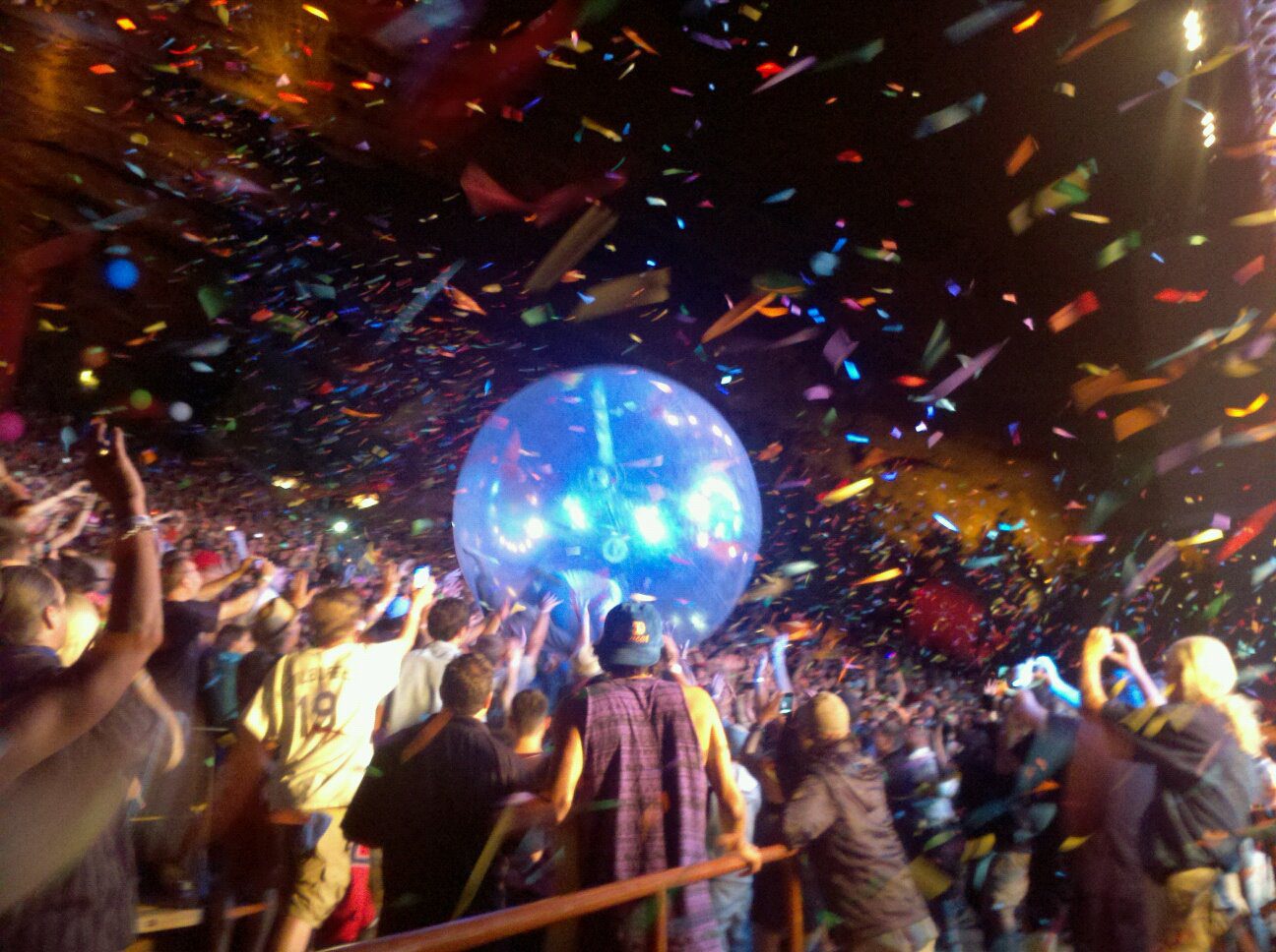 Concert crowd with confetti and giant ball.