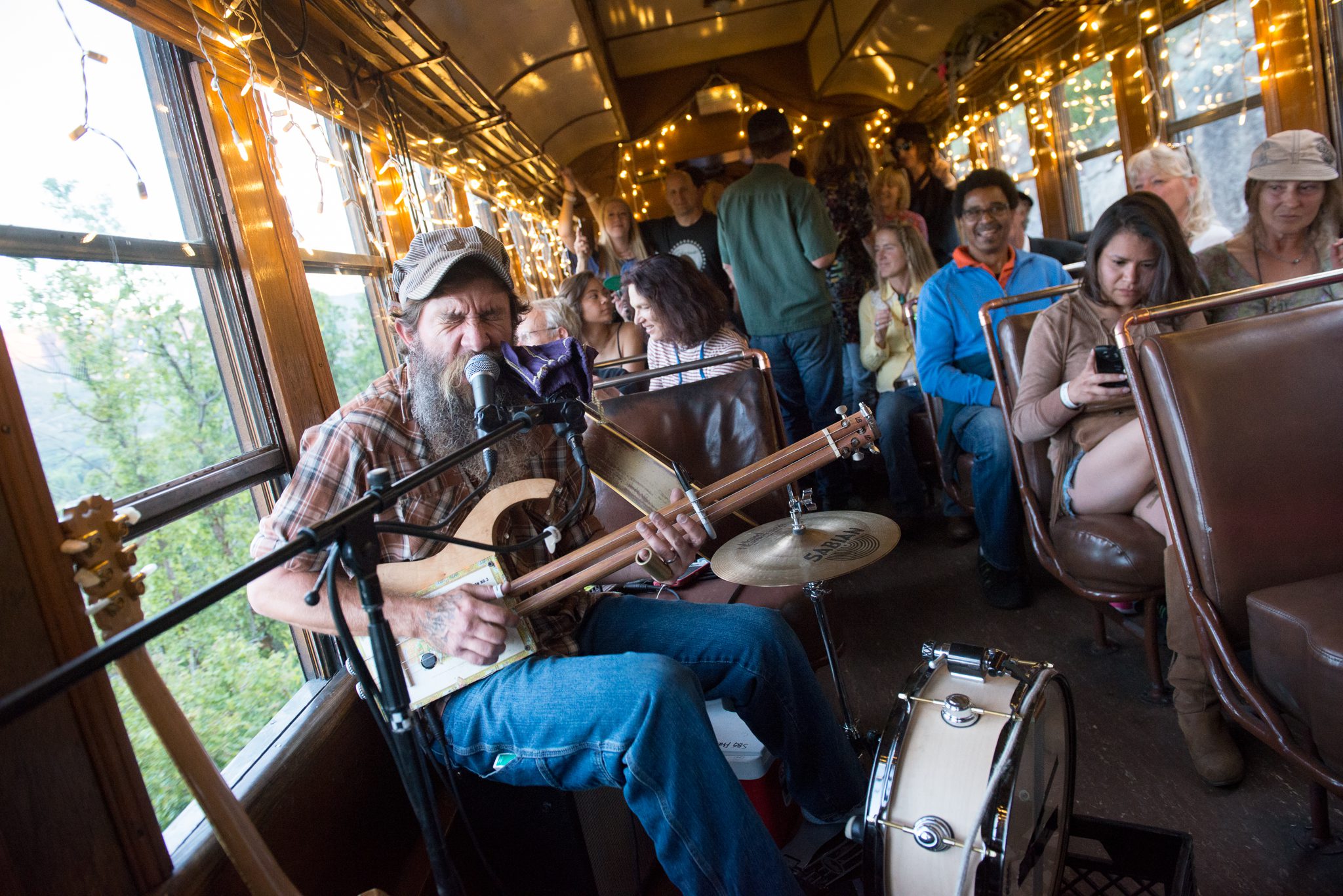 Musician performing on train with seated audience.