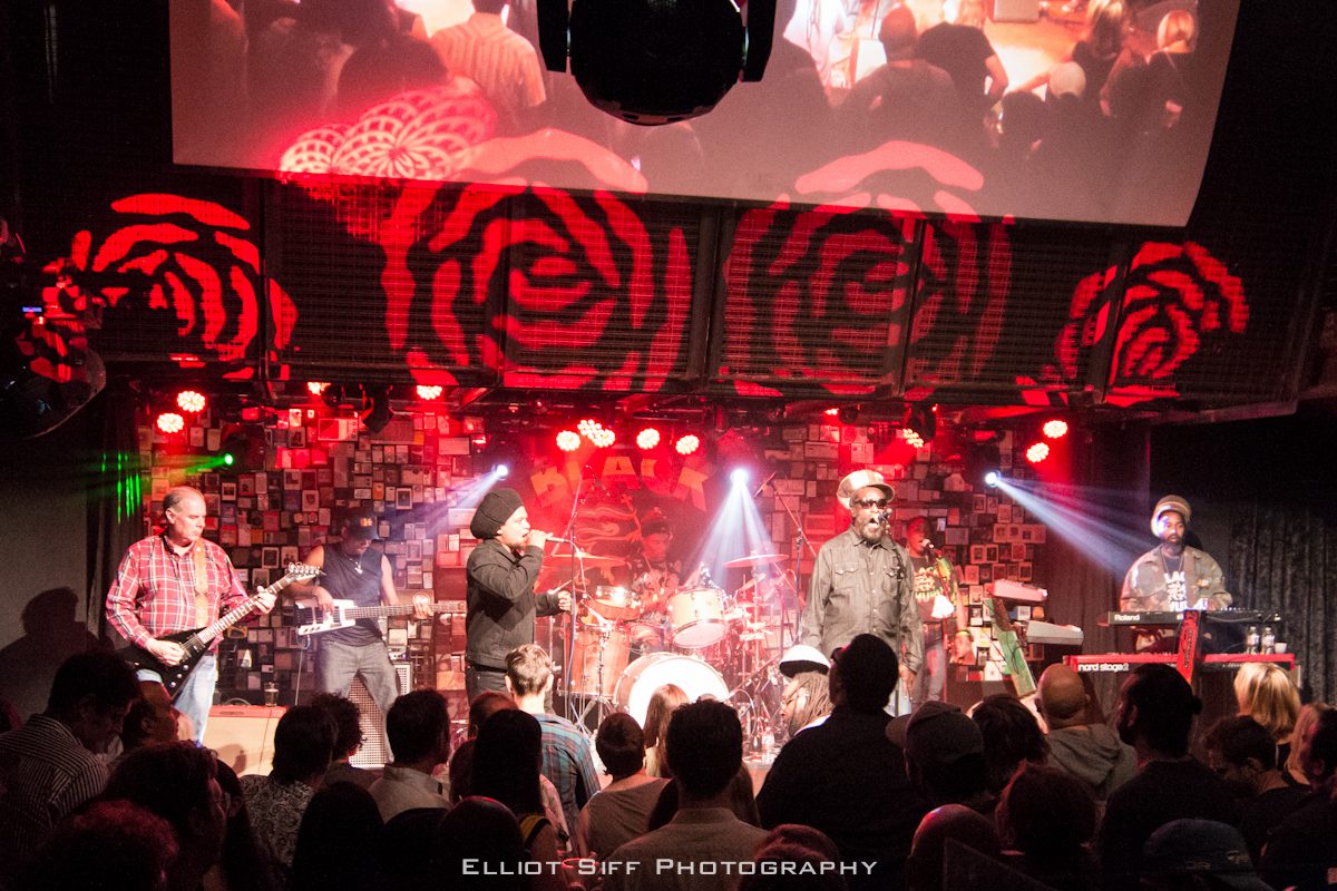 Band performing on stage with vibrant lights.