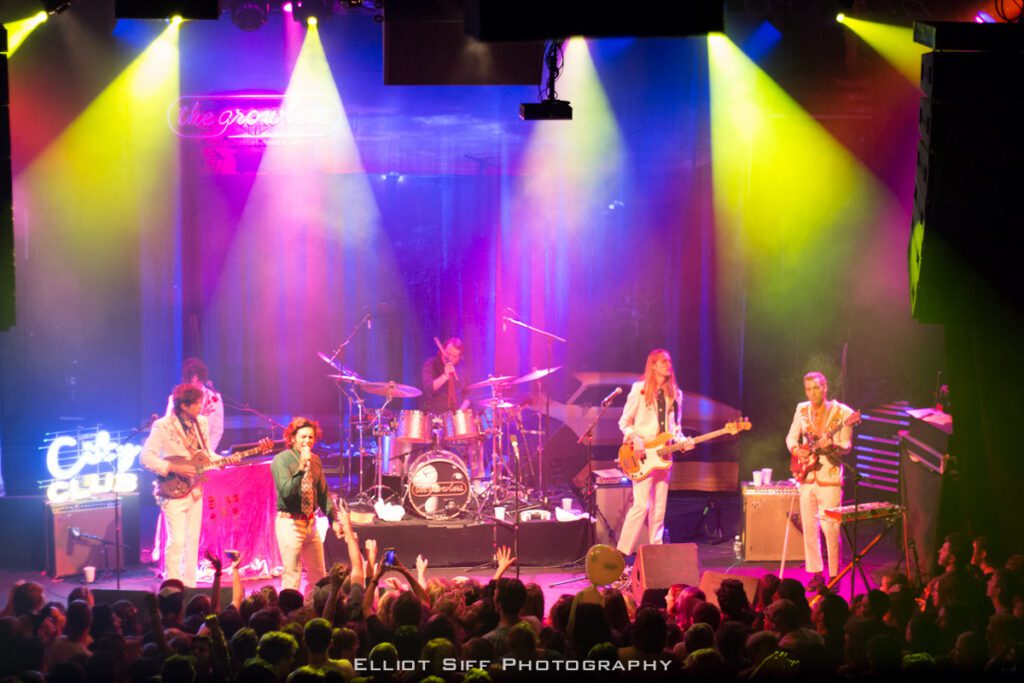 Band performing on stage with colorful lights.