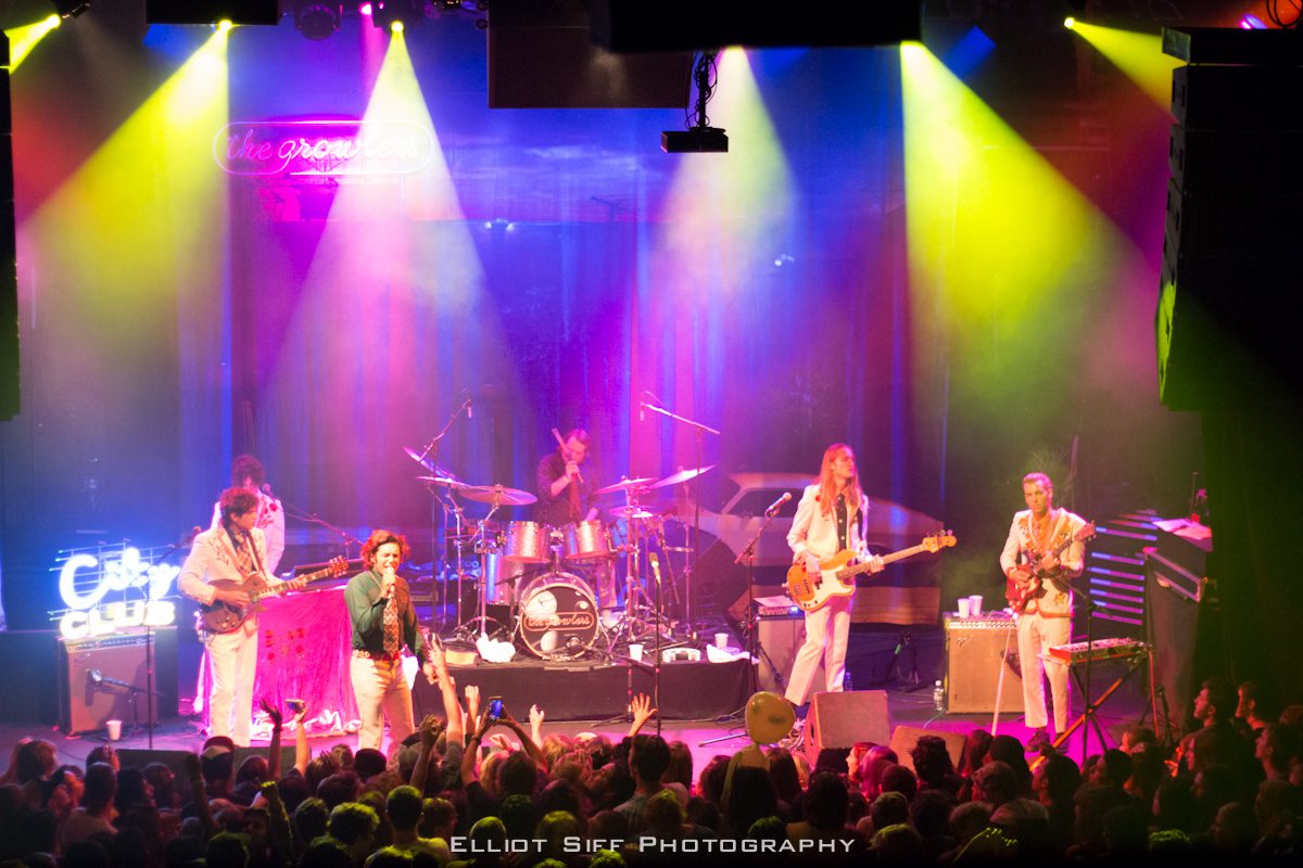 Band performing on stage with colorful lights.