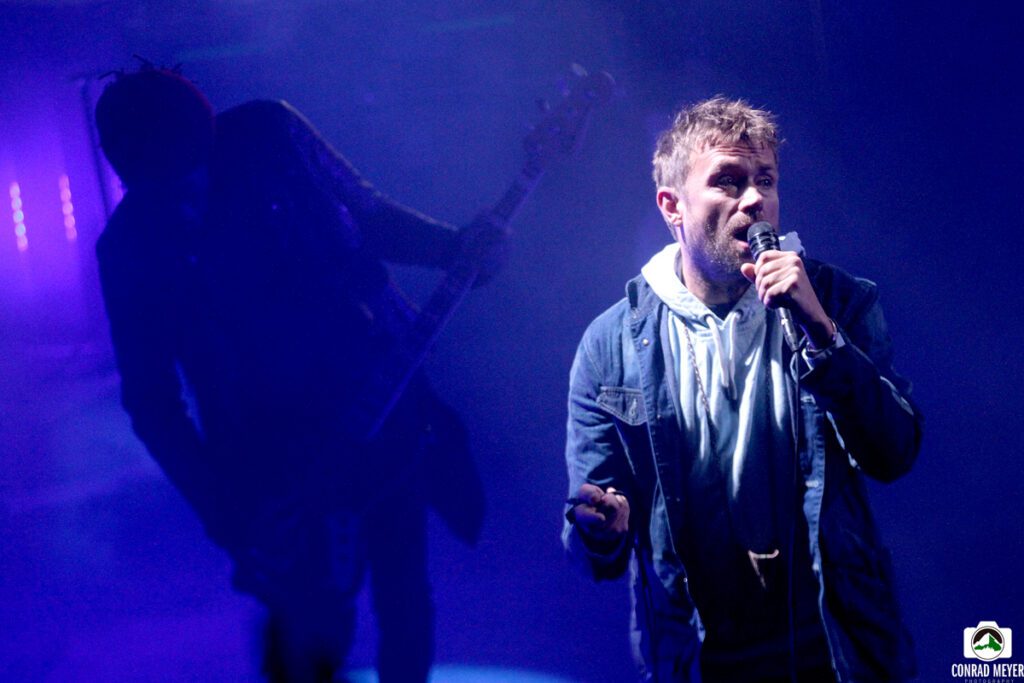 Singer performing live on stage with guitarist.