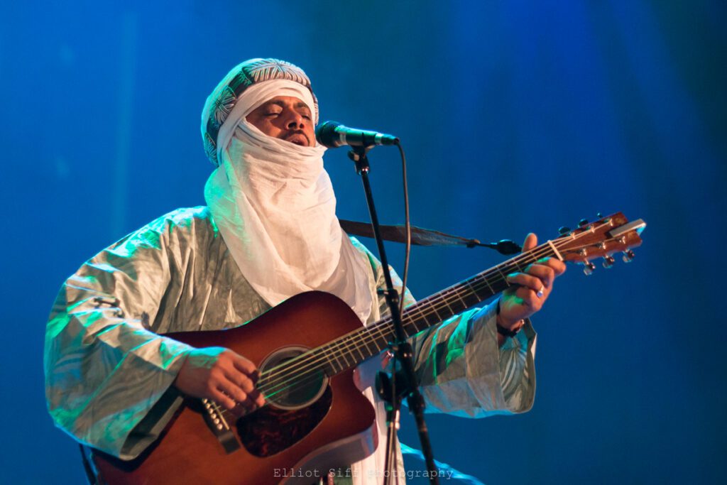 Musician in traditional attire playing guitar.