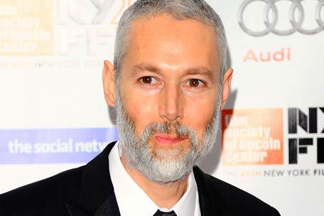 Man with gray beard at event backdrop.