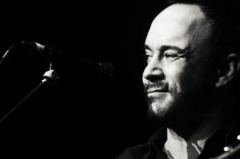 Man singing into a microphone, black and white.