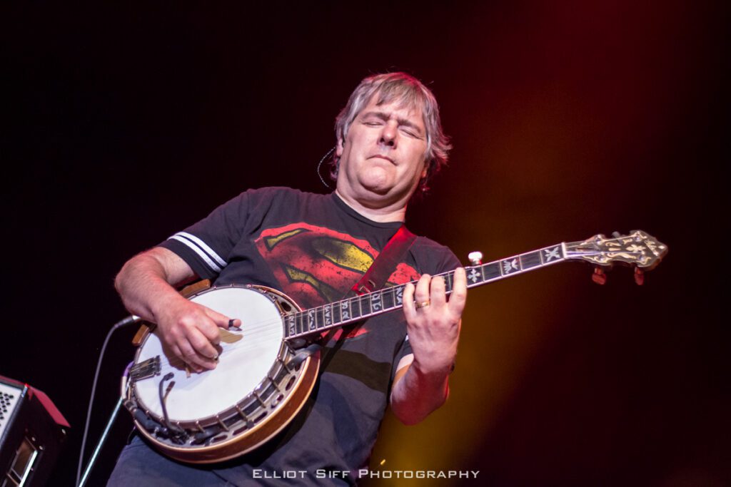 Musician playing banjo on stage.