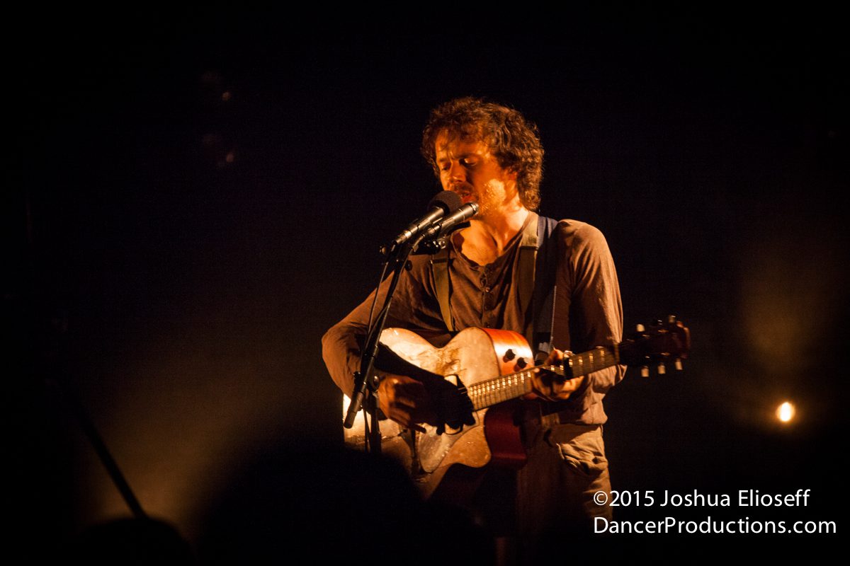 Musician performing on stage with guitar.