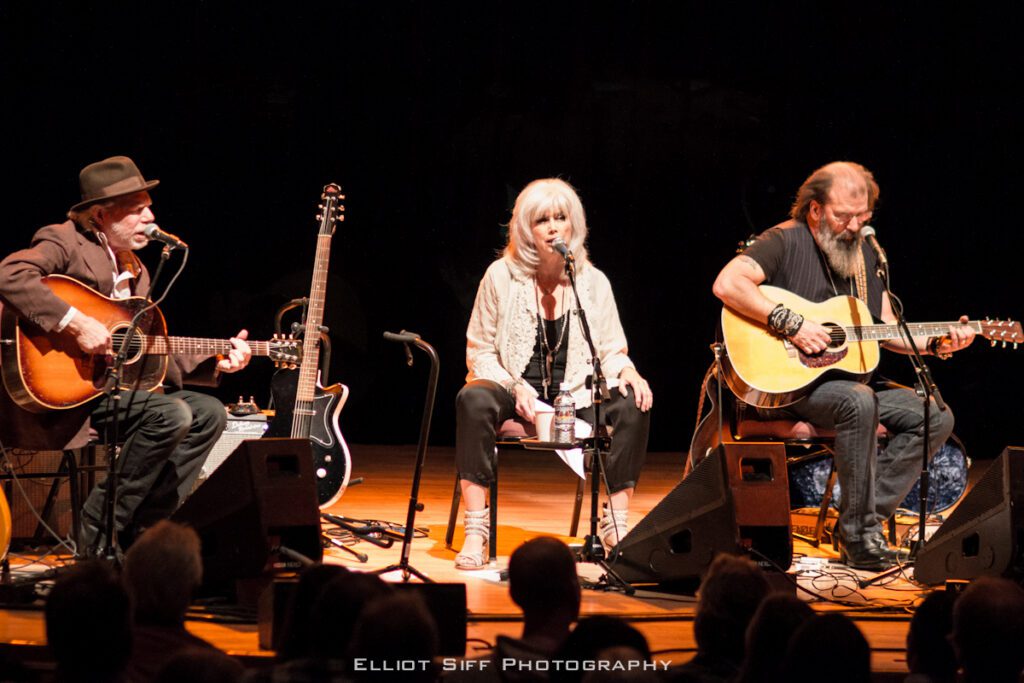 Three musicians performing on stage with guitars.