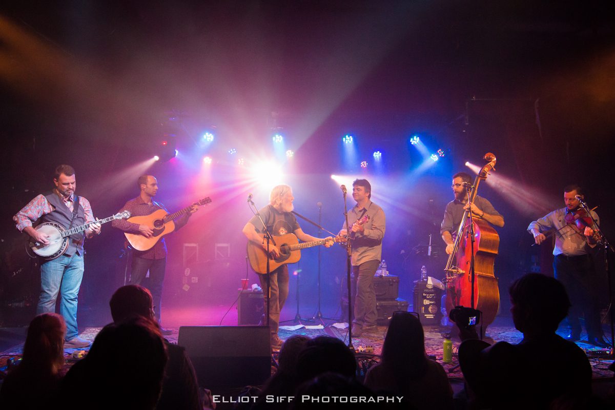 Band performing live on stage with instruments.