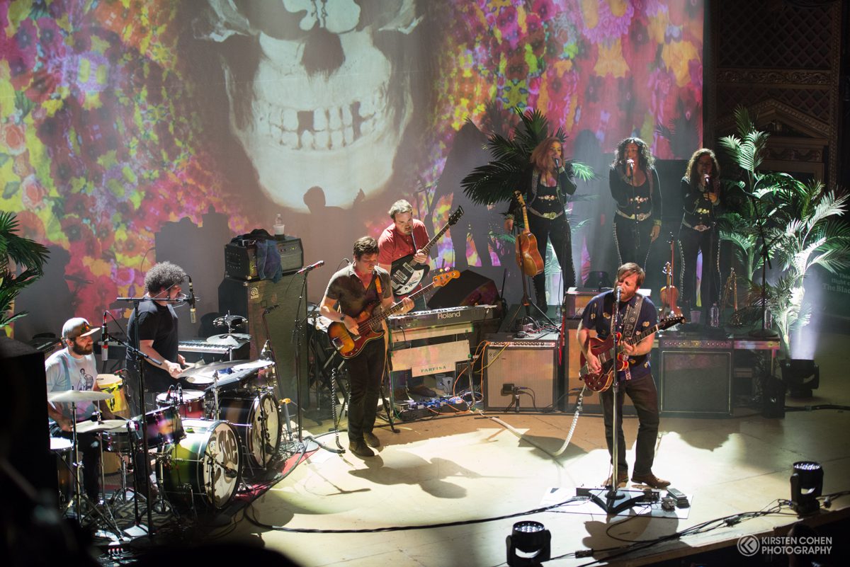 Band performing live with colorful stage backdrop.