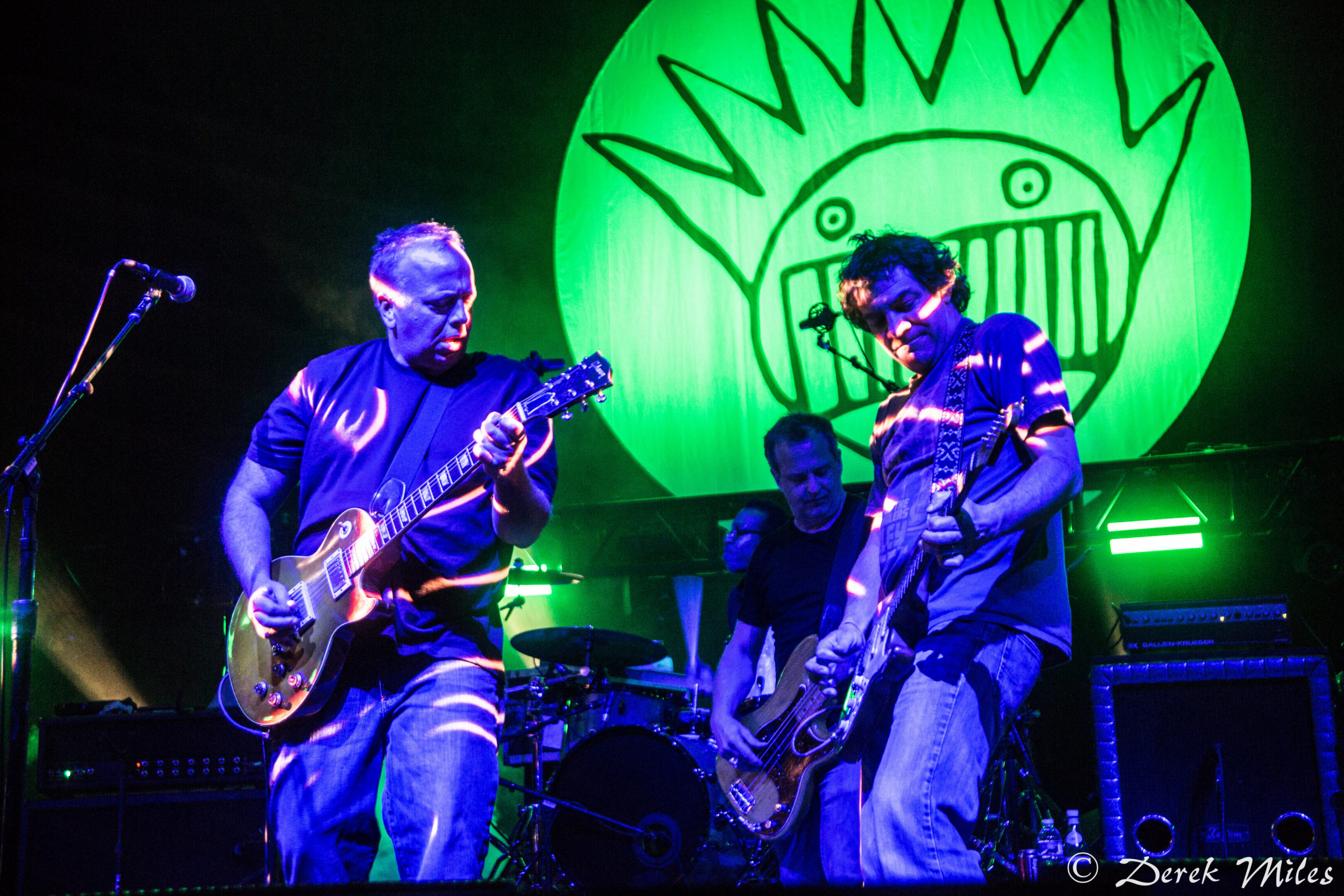 Band performing on stage with green lighting.