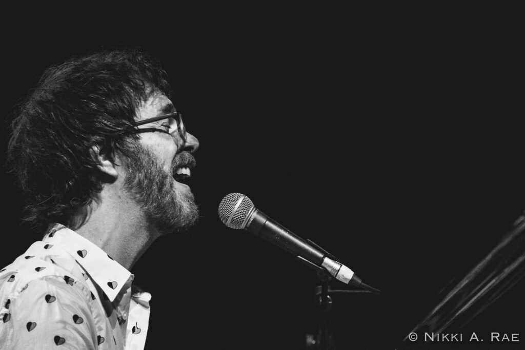 Musician singing passionately into a microphone.