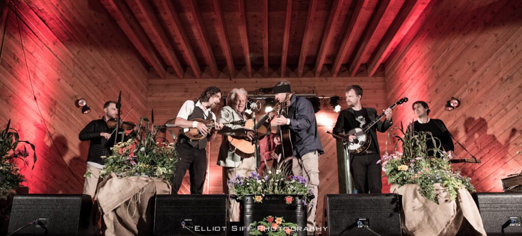 Musicians performing on a wooden stage.
