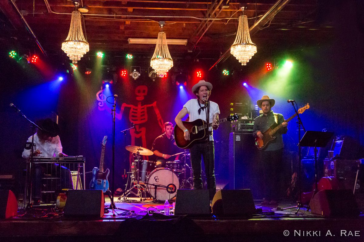 Band performing on stage with colorful lights.