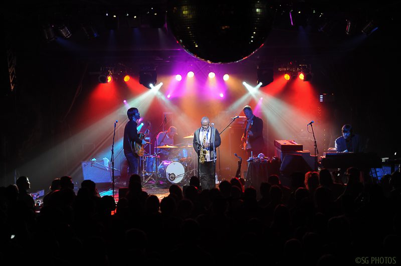 Live band performing on stage with lights.